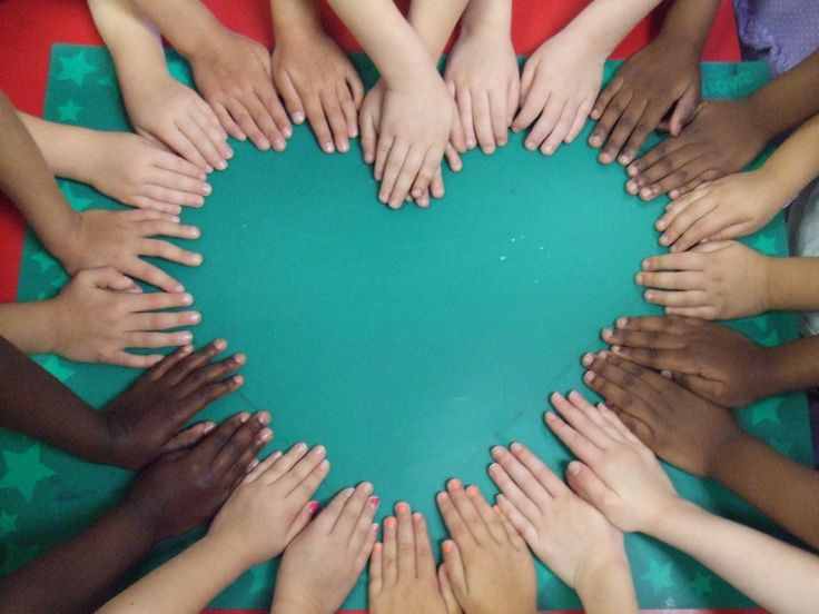 People of different backgrounds placing their hands together to form a heart.